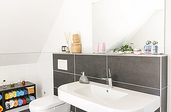 ECO System HAUS – Badezimmer mit dunkelgrauen Fliesen, Waschbecken und WC