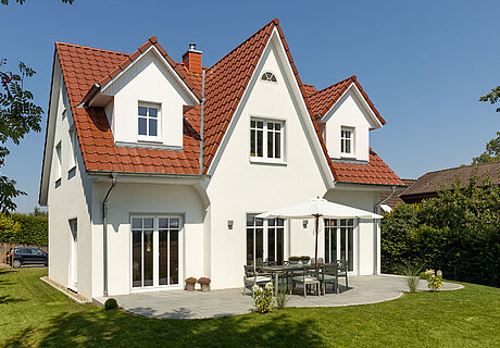 ECO System HAUS – Friesenhaus mit weißem Stein, weißen Fenstern und rotem Dach