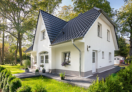 ECO System HAUS – Friesenhaus mit weißem Stein, weißen Fenstern und dunklem Dach