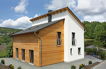 ECO System HAUS – Pultdachhaus mit weißem Stein, Holz und dunklem Dach