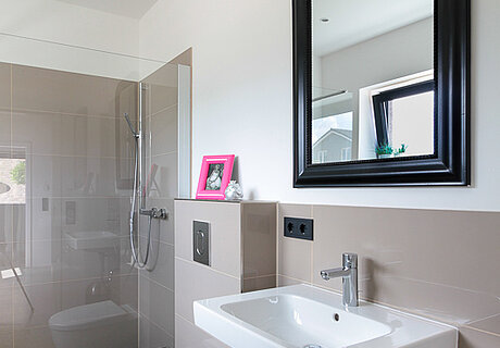 ECO System HAUS – Badezimmer in beige mit weißem Waschbecken und WC