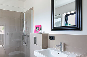 ECO System HAUS – Badezimmer in beige mit weißem Waschbecken und WC