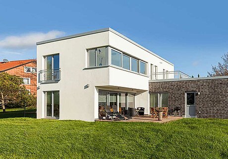 ECO System HAUS – Bauhaus Modern Classic mit weißem Stein, hellen Fenstern, Terrasse und Garten