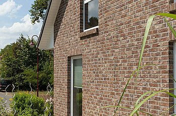 ECO System HAUS – Vario-Haus mit rotbraunem Stein und weißen Fenstern
