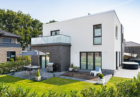 ECO System HAUS – Bauhaus Modern Classic mit dunklem und weißem Stein, dunklen Fenstern und großer Terrasse