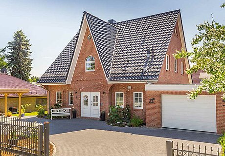 ECO System HAUS – Friesenhaus mit rotem Stein, dunklem Dach, hellen Fenstern und Garage