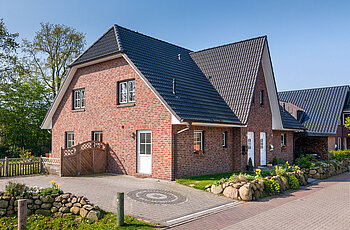 ECO System HAUS – Doppelhaus mit rotem Stein, dunklem Dach und dunklen sowie hellen Fenstern