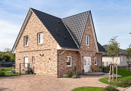 ECO System HAUS – Friesenhaus mit hellrotem Stein, weißen Fenstern, dunklem Dach
