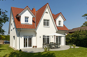 ECO System HAUS – Friesenhaus mit weißem Stein, weißen Fenstern und rotem Dach