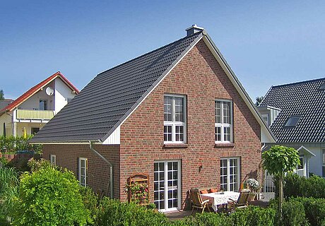 ECO System HAUS – Vario-Haus mit dunkelrotem Stein, dunklem Dach, weißen Fenstern und Terrasse