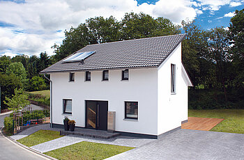 ECO System HAUS – Pultdachhaus mit weißem Stein, dunklem Dach und dunklen Fenstern und Türen
