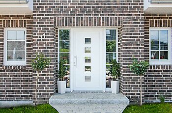 ECO System HAUS – Kapitänshaus mit graubraunem Stein und weißer Eingangstür