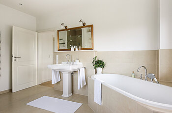 ECO System HAUS – Badezimmer in beige und weiß mit Badewanne und Waschbecken