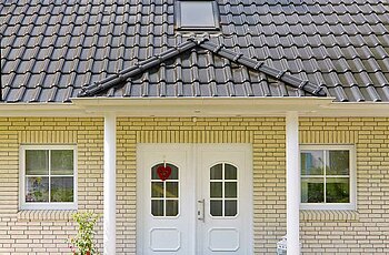 ECO System HAUS – Vario-Haus mit beigem Stein, dunklem Dach und weißer Haustür