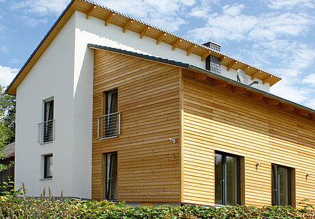 ECO System HAUS – Fassadengestaltung weißer Stein und braunes Holz