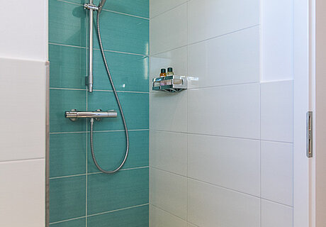 ECO System HAUS – Badezimmer mit weißen und türkisen Fliesen, Ansicht Dusche