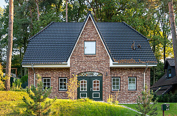 ECO System HAUS – Friesenhaus mit Garten, rotem Stein, hellen Fenstern und dunklem Dach