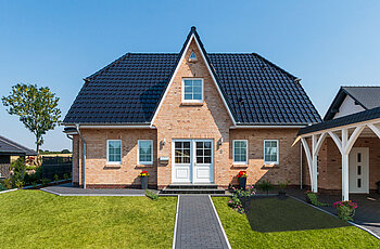 ECO System HAUS – Friesenhaus mit hellrotem Stein, weißen Fenstern und dunklem Dach