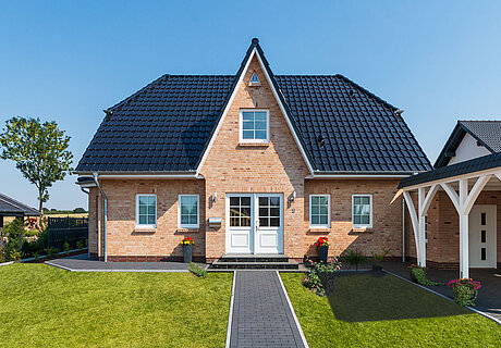ECO System HAUS – Friesenhaus mit hellrotem Stein, weißen Fenstern und dunklem Dach