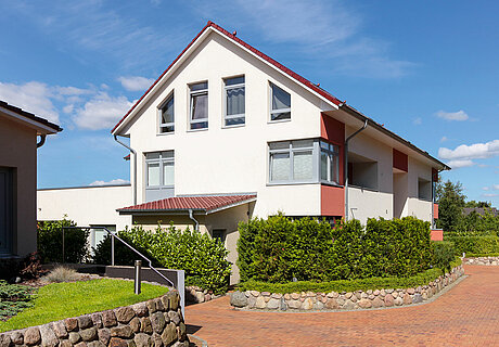 ECO System HAUS – Mehrfamilienhaus in rot und weiß mit dunklem Dach