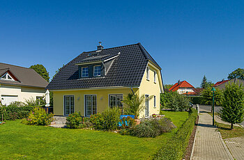 ECO System HAUS – Vario-Haus mit gelbem Stein, dunklem Dach und Garten
