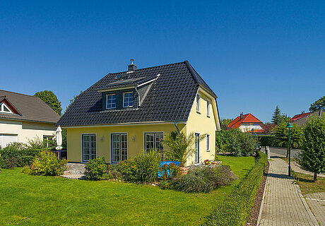 ECO System HAUS – Vario-Haus mit gelbem Stein, dunklem Dach und Garten