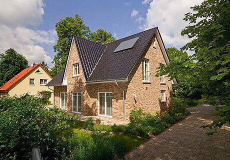 ECO System HAUS – Friesenhaus mit rotem Stein und dunklem Dach und mit Garten