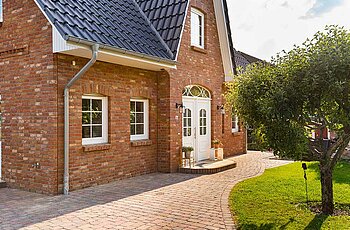 ECO System HAUS – Friesenhaus mit rotem Stein, weißen Fenstern und dunklem Dach