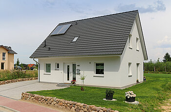 ECO System HAUS – Vario-Haus mit weißem Stein, weißen Fenstern, dunklem Dach und Vorgarten
