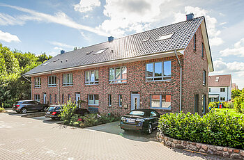 ECO System HAUS – Mehrfamilienhaus mit rotem und dunklem Stein und dunklem Dach
