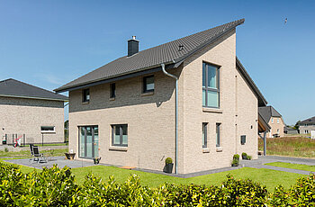 ECO System HAUS – Pultdachhaus mit hellem Stein, dunklem Dach und Terasse