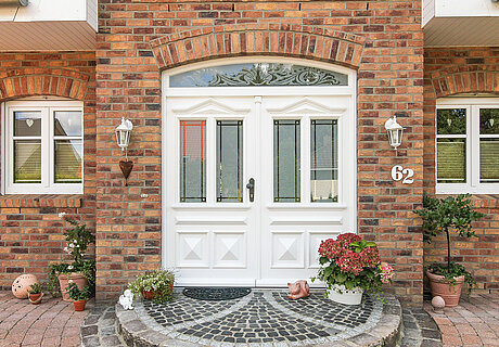 ECO System HAUS – Friesenhaus Eingangsbereich mit weißer Tür und rotem Stein