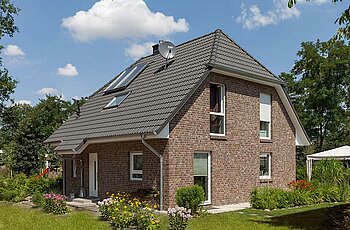 ECO System HAUS – Vario-Haus mit rotbraunem Stein, dunklem Dach, weißen Fenstern und Garten