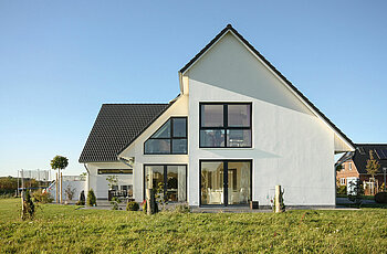 ECO System HAUS – Vario-Haus mit weißem Stein, dunklem Dach, dunklen Fenster und Garten