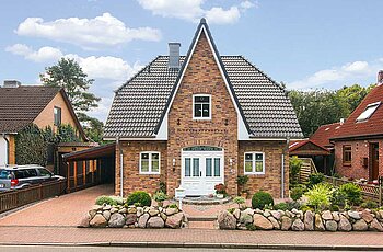 ECO System HAUS – Friesenhaus mit rotem Stein, dunklem Dach und weißen Türen und Fenstern, Vorderansicht