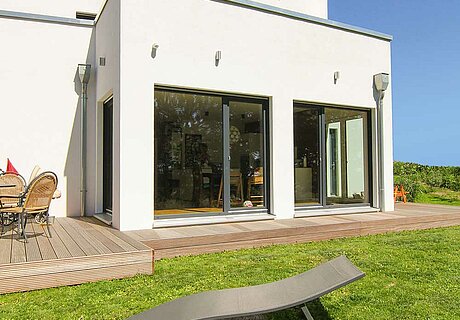 ECO System HAUS – Bauhaus Modern Classic mit weißem Stein und dunklen Fenstern, Gartenansicht