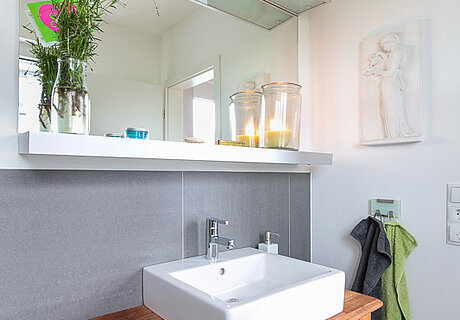 ECO System HAUS – Badezimmer mit Waschtisch, graue Fliesen, brauner Tisch