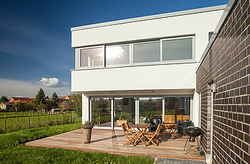 ECO System HAUS – Bauhaus Modern Classic mit weißem Stein und hellen Fenstern, Terrassenansicht