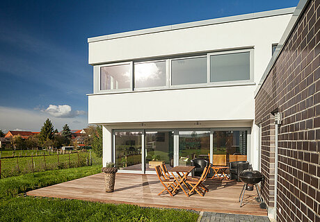ECO System HAUS – Bauhaus Modern Classic mit weißem Stein und hellen Fenstern, Terrassenansicht